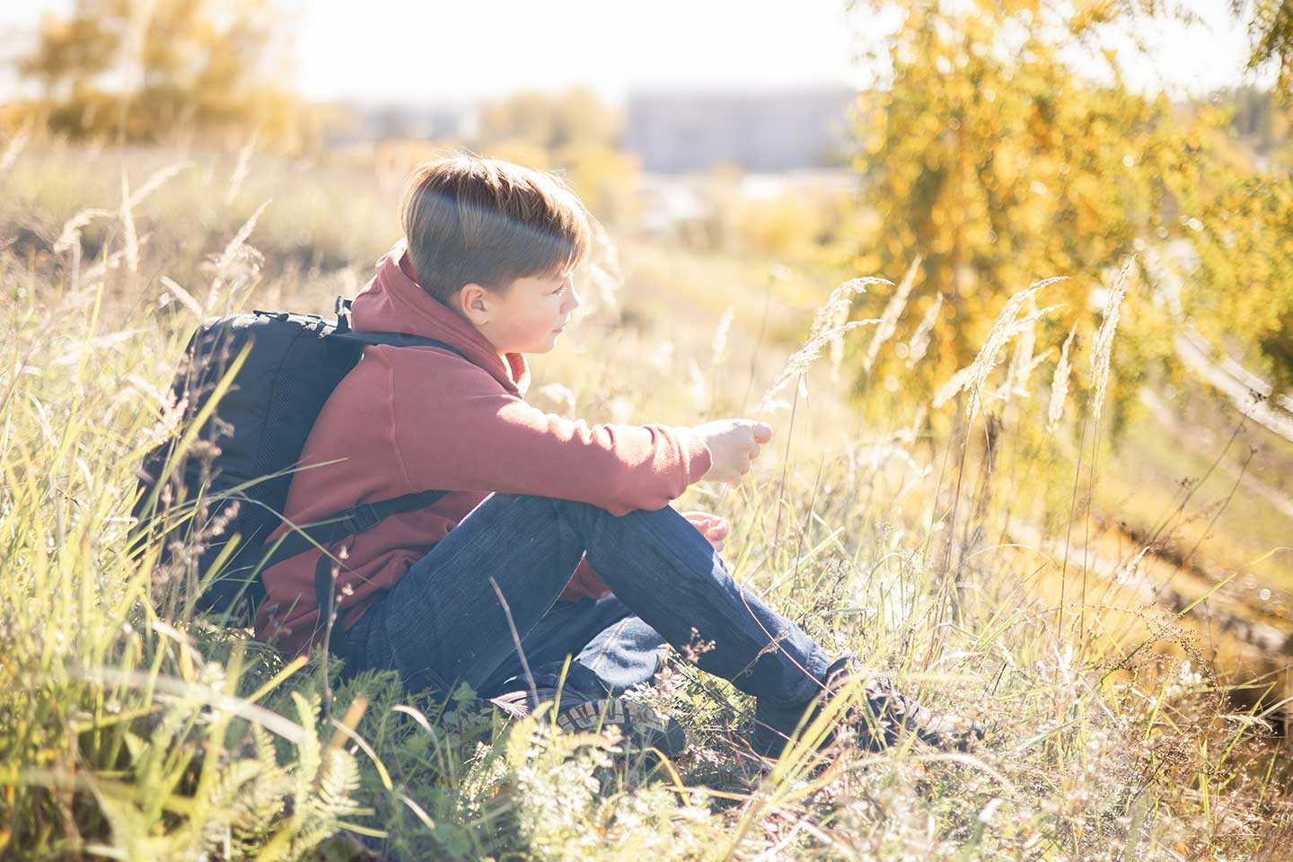 autumn-portrait-of-teenager-boy-with-backpack-sitt