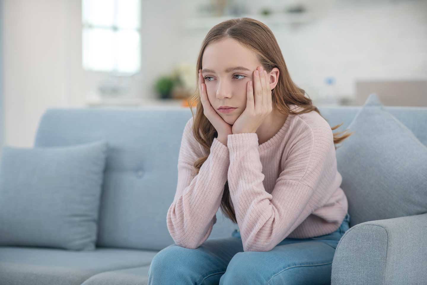 sad-teenager-girl-sitting-at-home-on-the-couch