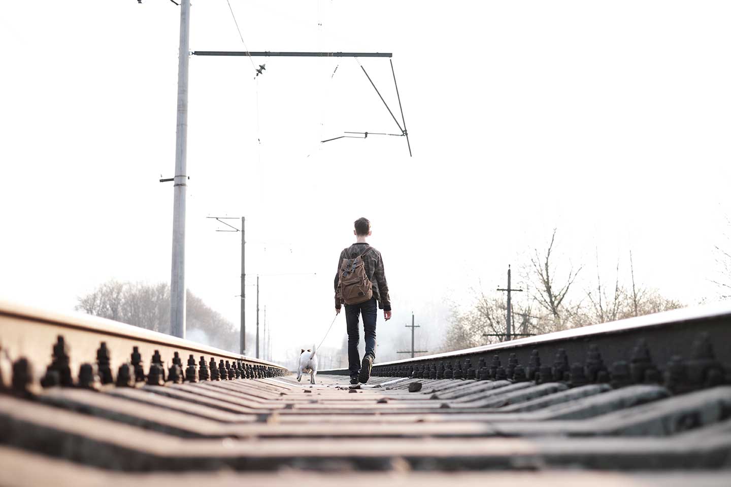 teenager-on-railway-walking-with-small-white-dog